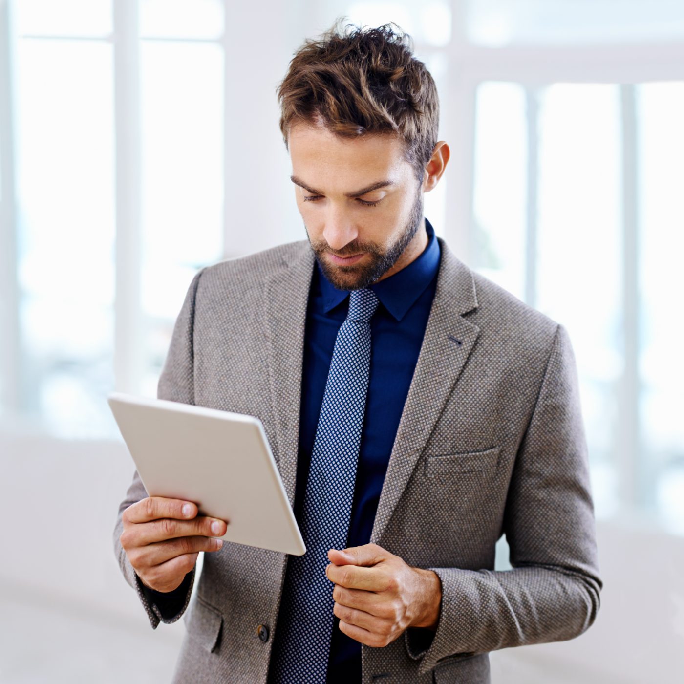 Manager in a grey blazer reviewing team task progress on a tablet